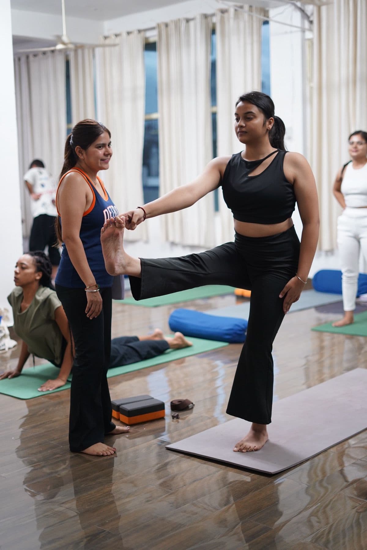 Shilpa hands-on, adjusting a student's standing balance in class